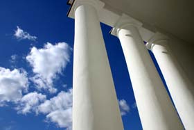 A few clouds on a bright blue sky viewed through the columns of a Roman building where announcements of the day were made.