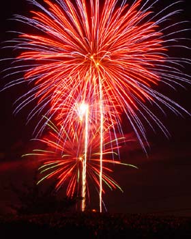 Bright red shower of fireworks exploding on a black sky to draw attention to the event of the day.