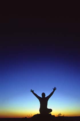 The first instant of sunrise silhouettes a man reaching up into the indigo sky as though reaching into the light for knowledge to drive away the darkness.