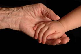 Hands of the grandparent and child touching showing continuity from conception to retirement.