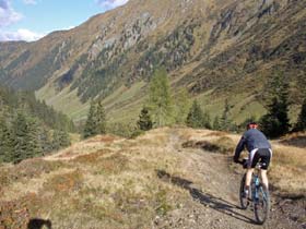 Mountain biker on a dirt path about to descend and find her way into a majestic mountain valley.  Let Breakthrough NPD help you find the best route to explore this immense world of potential.